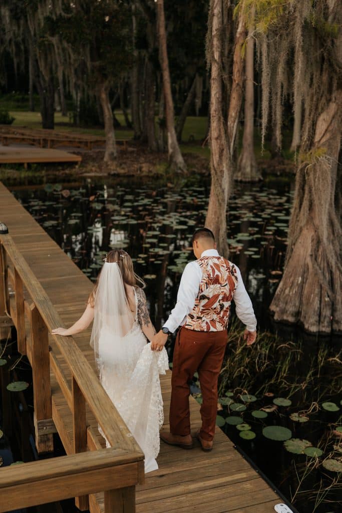 Bride and groom on a wooden dock over a lake with lily pads