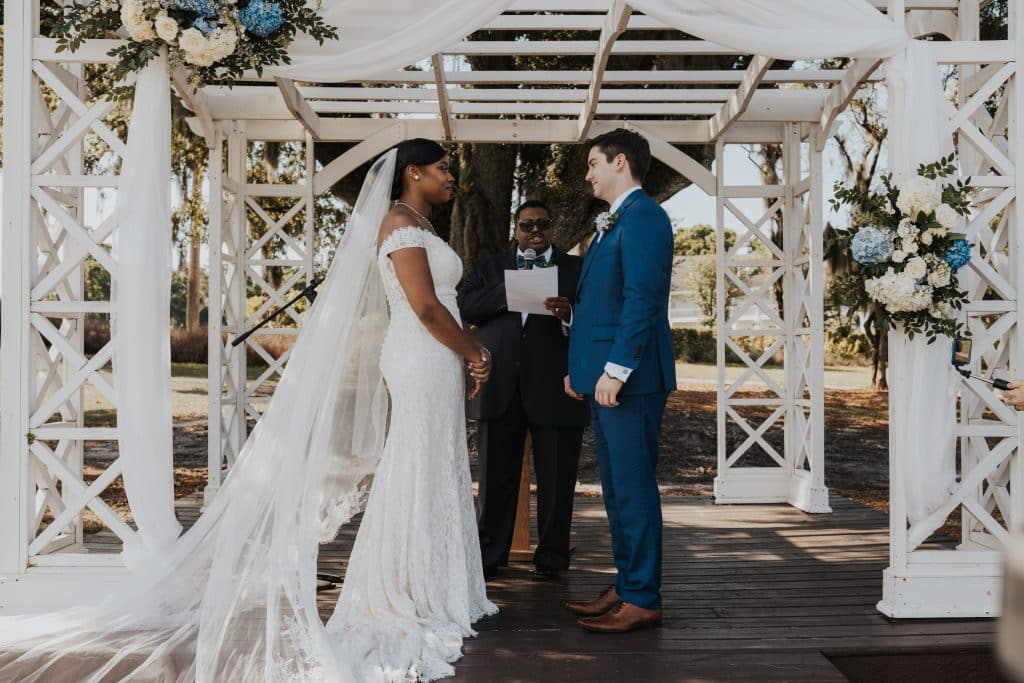 bi-racial couple with their officiant under the white pergola during the ceremony, Tuscawilla Country Club, Orlando, FL