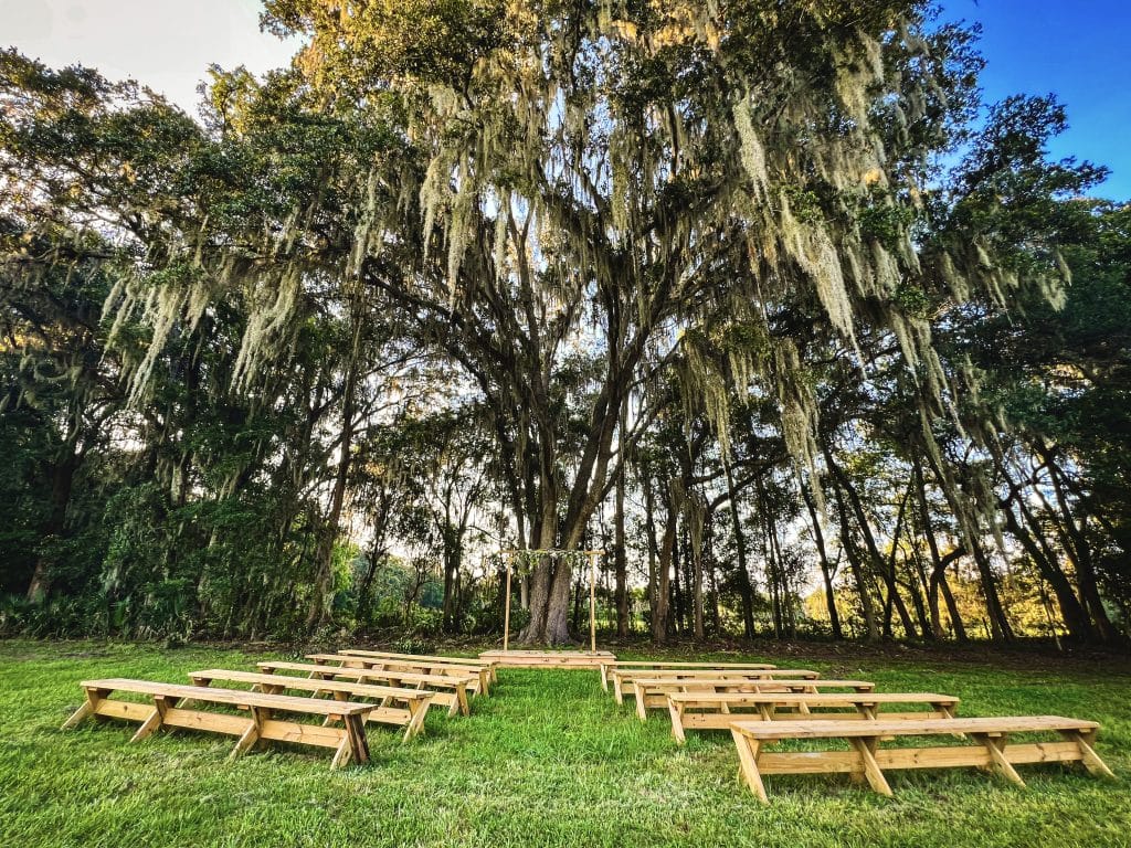 outdoor wedding ceremony, wood benches, large trees overarching the open field area, Orlando, FL
