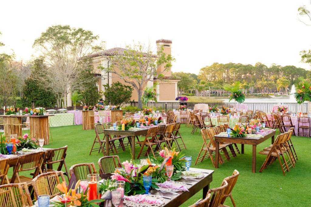 reception set up, outdoors, wood tables with wood chairs, multicolor flower centerpieces, green turf, Four Seasons Orlando at Walt Disney World Resort