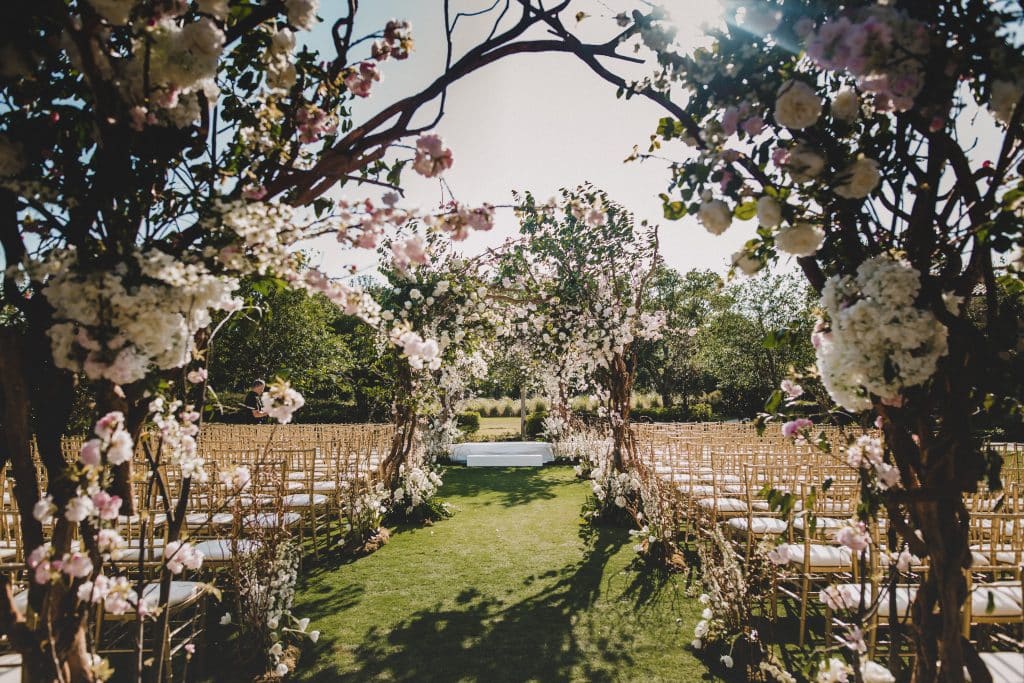a view of the wedding ceremony set up through the cherry blossom trees, wooden chairs, Orlando