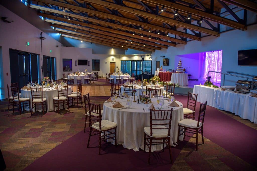reception set up, purple and blue uplighting, white tablecloths, wedding cake table in the distance, buffet tables on the right, Orlando, FL