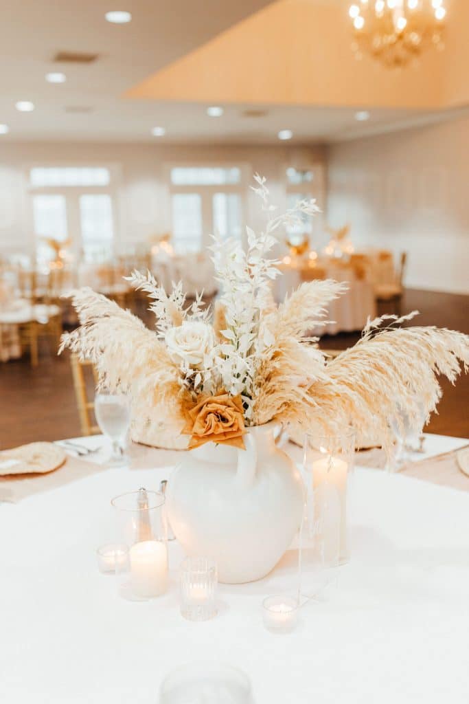 floral centerpieces with burnt orange flowers, champagne feathers, white votive candles around the centerpiece, Orlando, FL