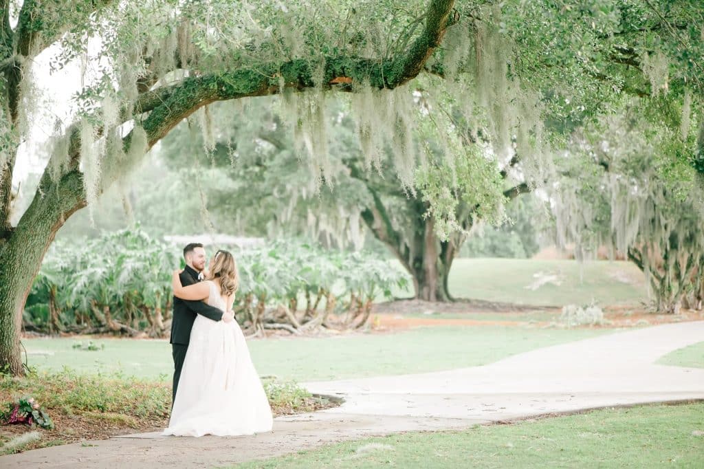 bride and groom standing under a weeping willow tree on the venue property, Tuscawilla Country Club, Orlando, FL