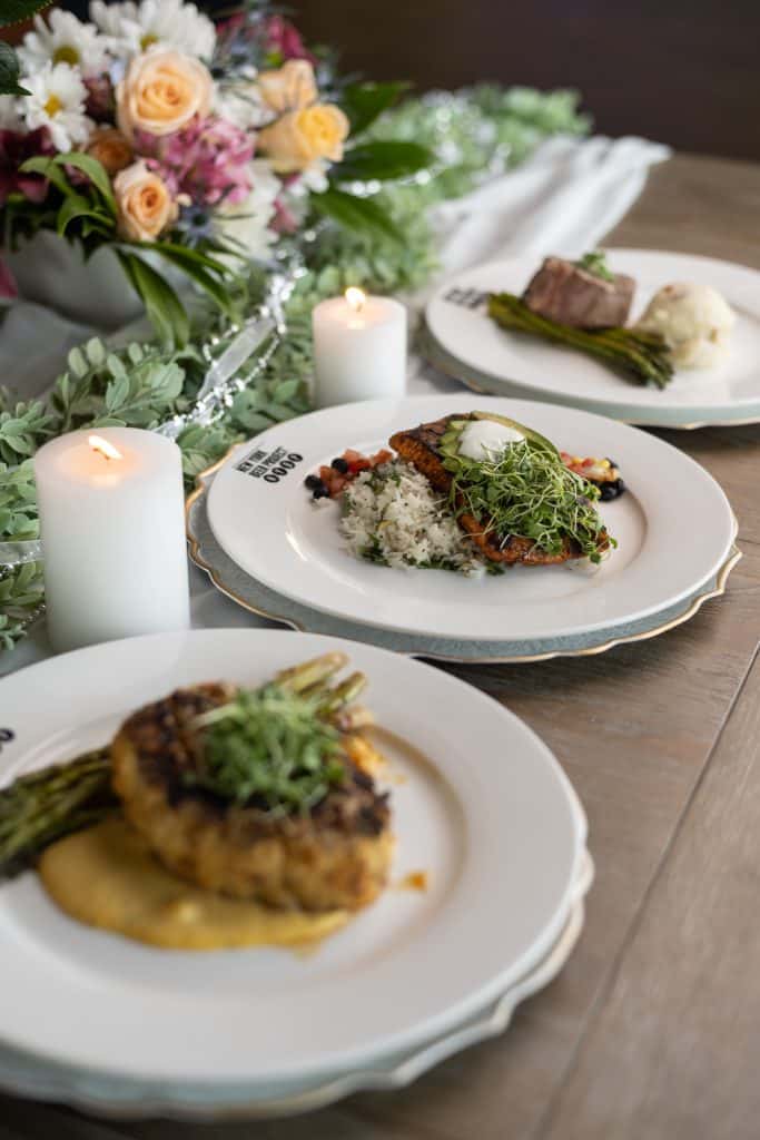 salmon, chicken and steak entrees on white plates, white candles, colorful, flower arrangement, Orlando, FL