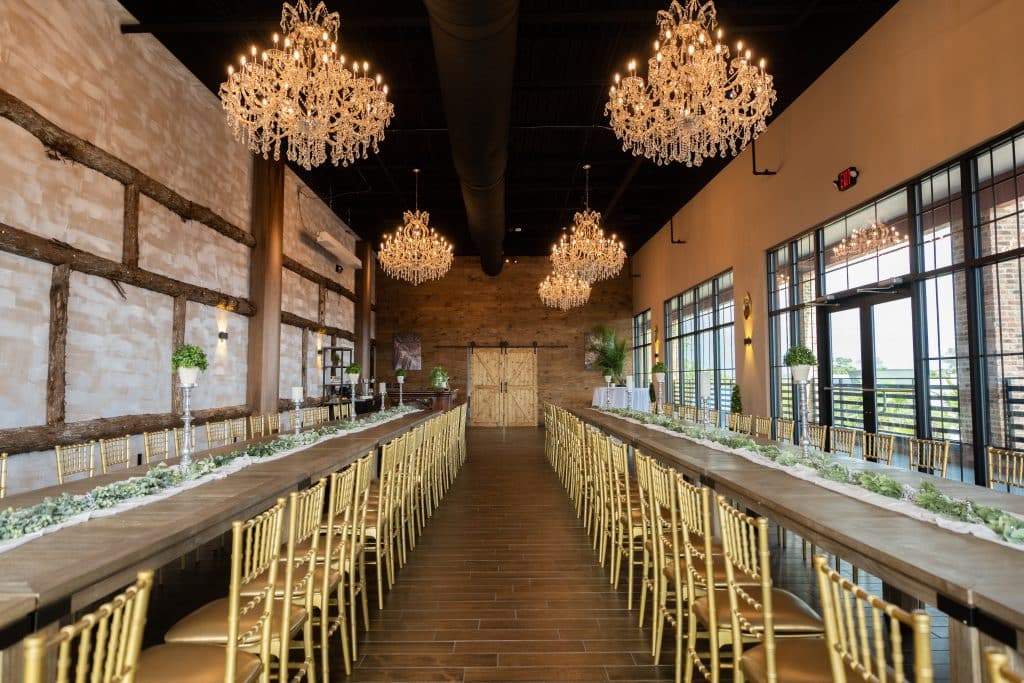 Room length tables, white table runners, wooden chairs, chandeliers above, large windows on the right side of the room, Orlando, FL