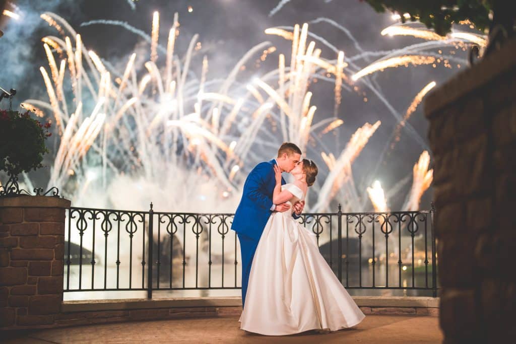 Bride and groom kissing on the balcony, fireworks in the backdrop, black iron fence, Central FL