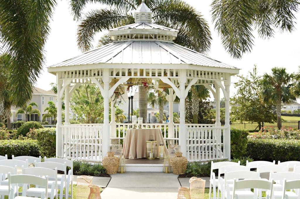 Gazebo with white chairs set up for the ceremony, white carpet in the aisle, small table with tan tablecloth at the front, Rentyl Resorts, Orlando, FL