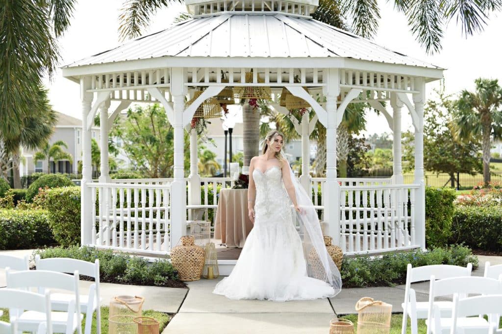 bride posing at the altar in front of the gazebo, at the ceremony set up, outdoors, beautiful backdrop of trees, Orlando, FL