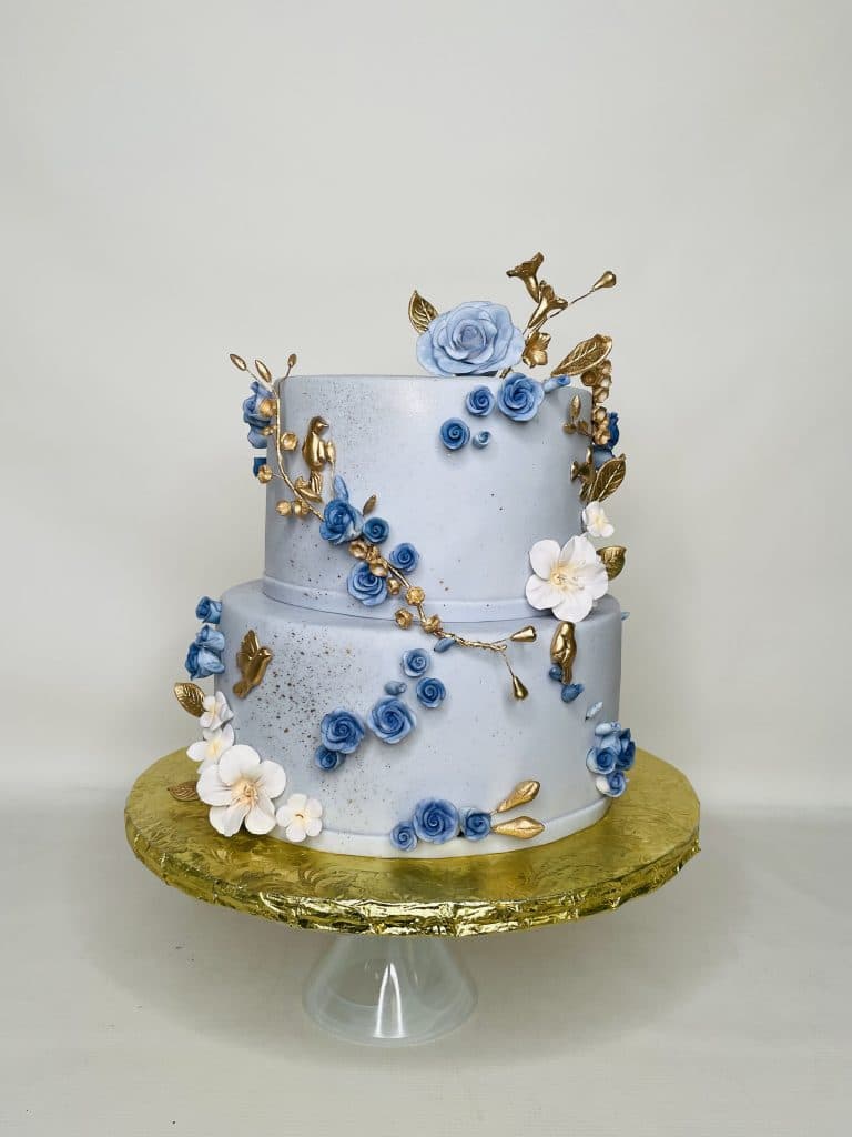 two layer cake, light blue fondant with gold, white and blue flowers along the sides, gold covered cake stand, orlando, FL