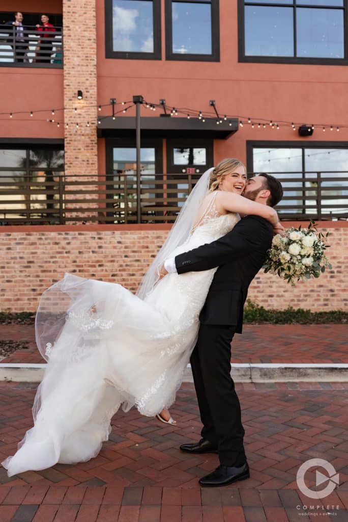 Bride and Groom outside, groom lifting his bride while kissing her on a brick walkway, Orlando, FL