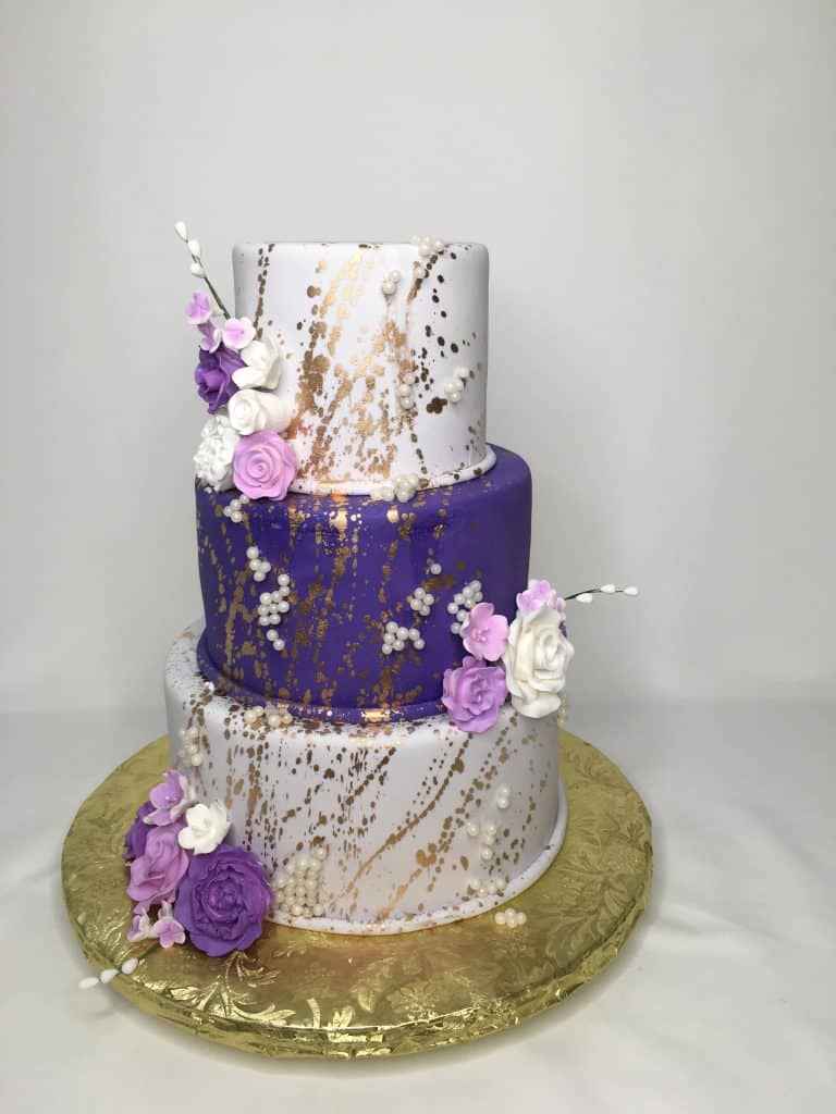 three layers, top and bottom are white fondant, middle layer is purple, pink, purple and white flowers on the top and bottoms of the layers, golf splashes across all layers, Sugar Divas Cakery, Orlando, FL