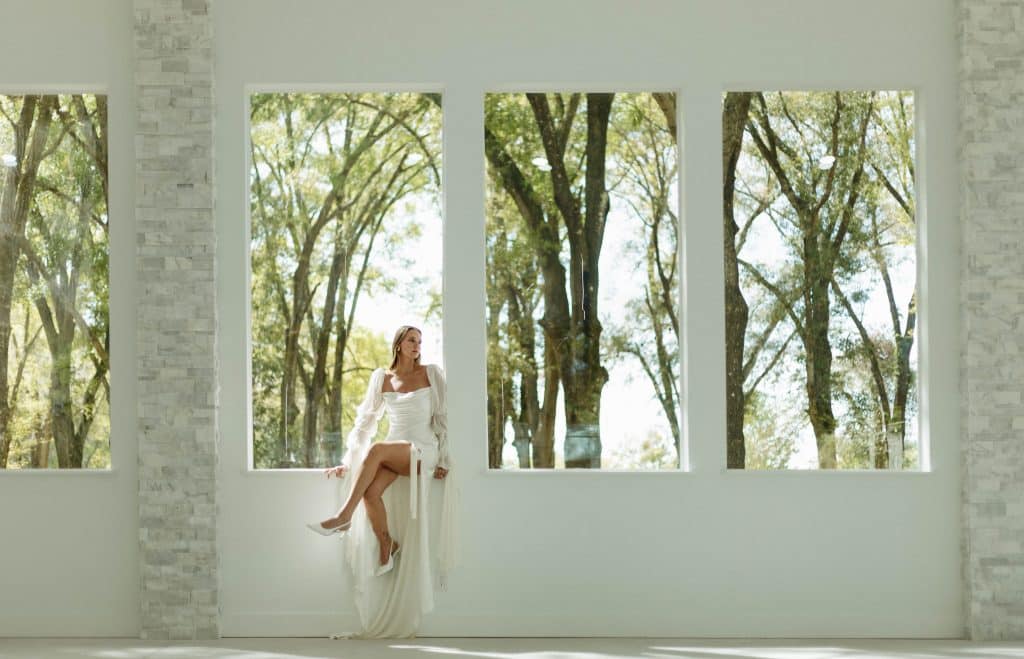 bride sitting on the windowsill at the indoor venue, The Whitewood Ranch, Orlando, FL