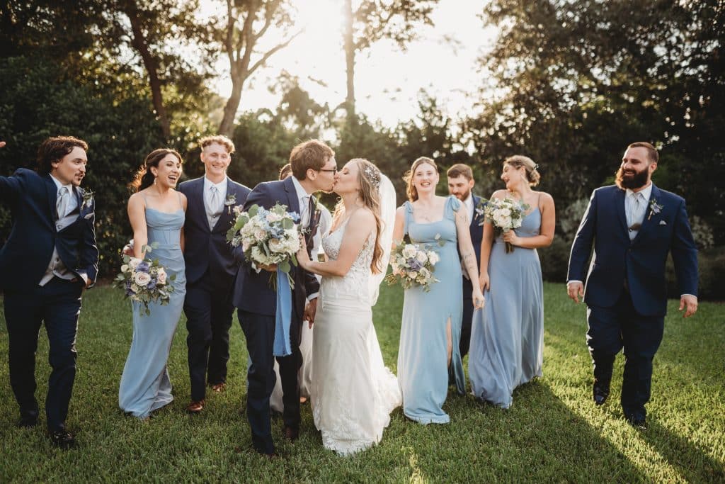 bride and groom kissing while their wedding party stands behind them, Orlando, FL