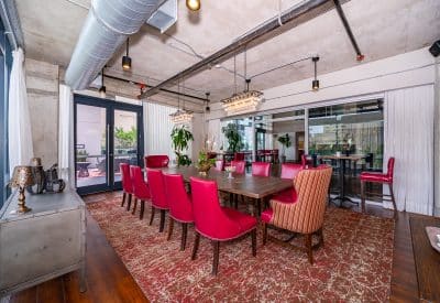 large table set for 12 with red chairs, long wooden table, exposed pipes, glass doors, Eola View, Orlando, FL