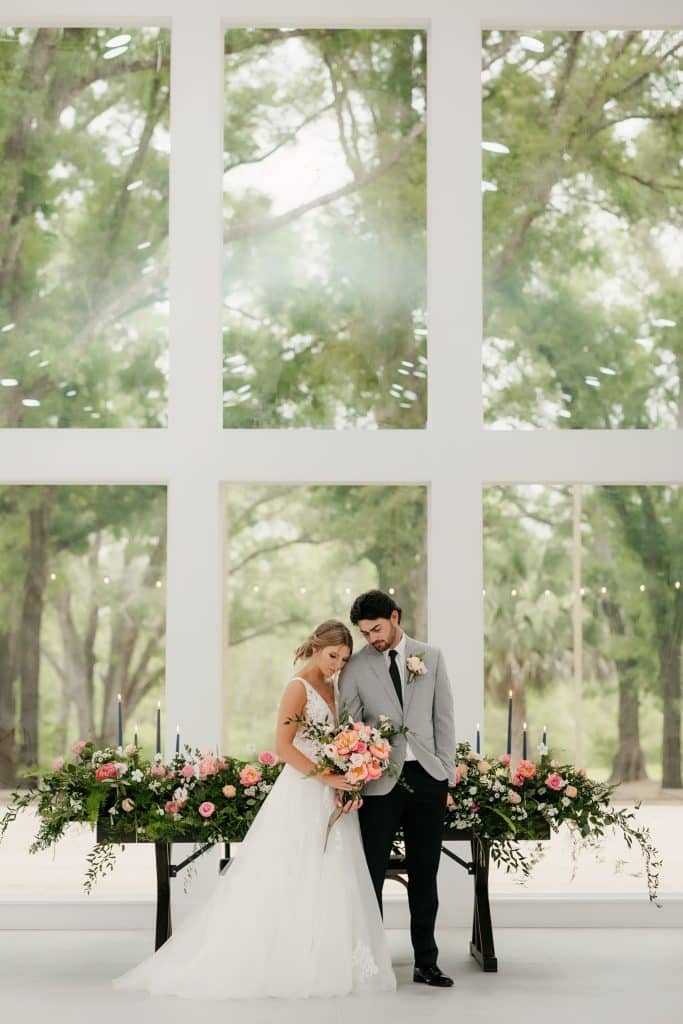 bride and groom standing in front of large windows, with their head table behind them, The Whitewood Ranch, Orlando, FL