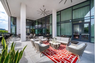 outdoor patio area, red and white carpet under the patio furniture, large plant in the corner, ceiling fans, large windows, Orlando, FL