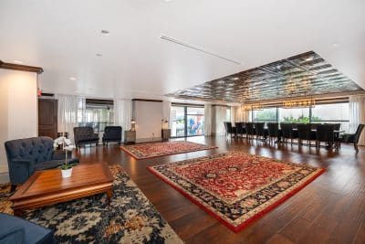 large open area, long table and chairs, seating for 16-18, coffee table with two blue chairs on the side, large floor rugs over the wood floors, Orlando, FL