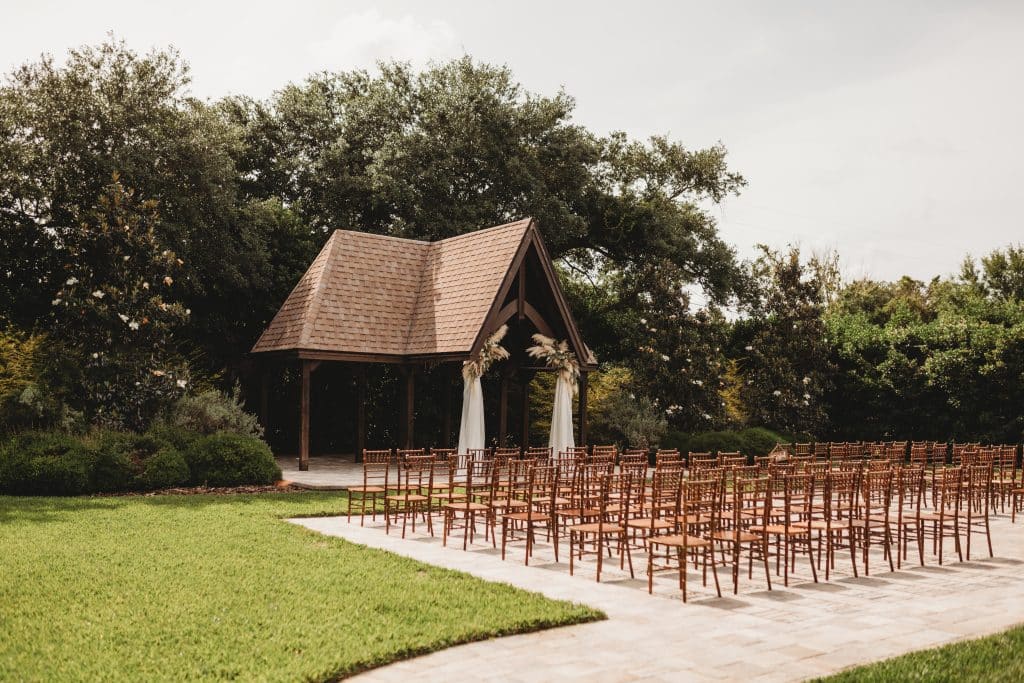 view from the side of the wedding ceremony set up, wooden chairs on pavement with grass surrounding, Orlando, FL