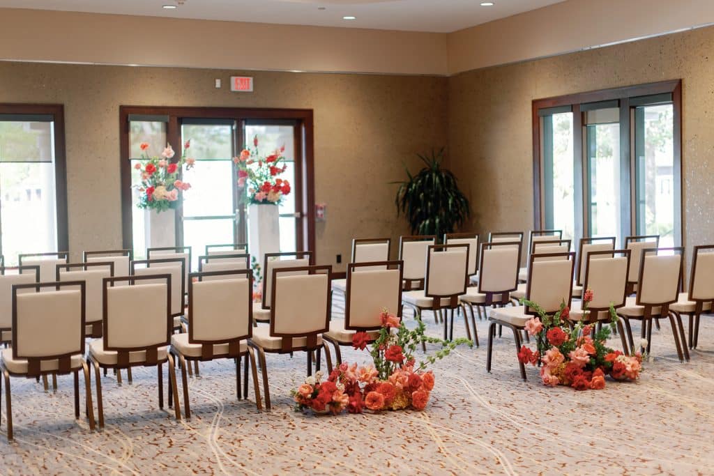 indoor wedding ceremony set up, rows of chairs with an altar at the front, orange and red flowers, Orlando, FL