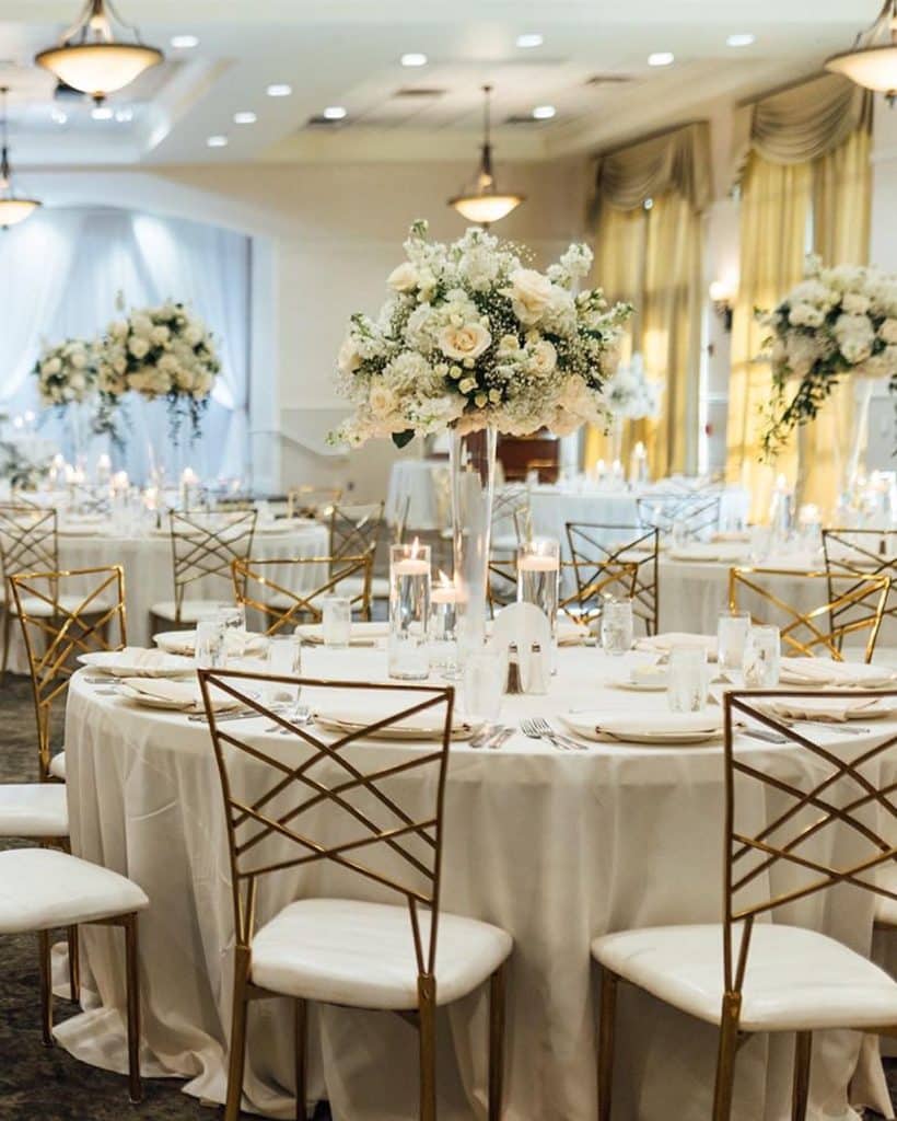 wedding reception set up, floral arrangement centerpieces that are towering over the tables, white tablecloths, candles, Orlando, FL