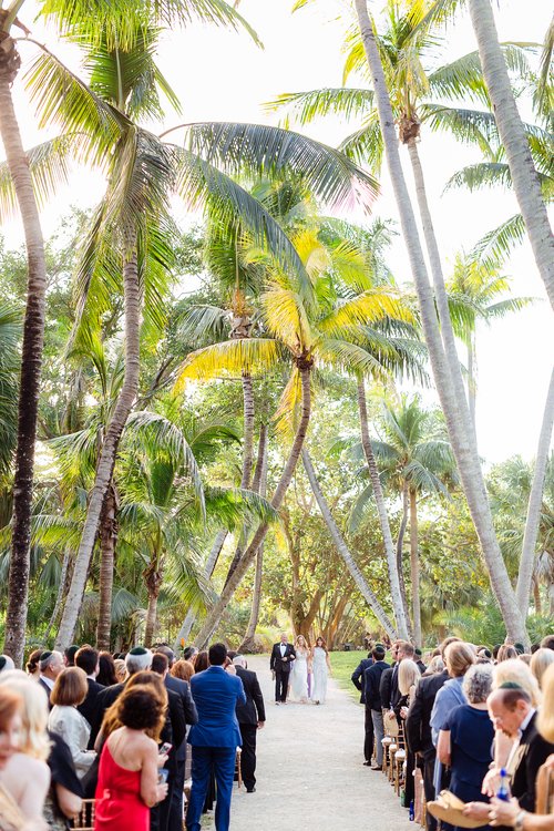 outdoor ceremony, palm trees, guests watching as the bride is escorted by her parents down the aisle, Orlando, FL