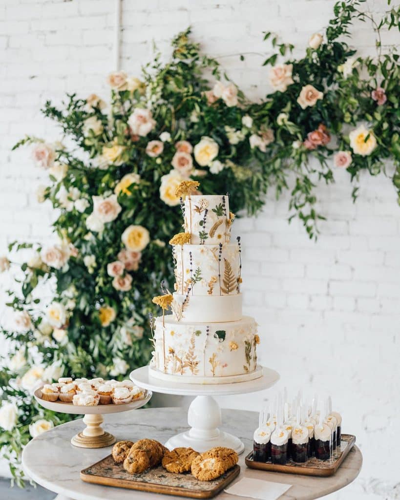 3 tier wedding cake display with other desserts, floral arrangement cascading behind on the wall, Lillie Shawn Imagery, Orlando, FL