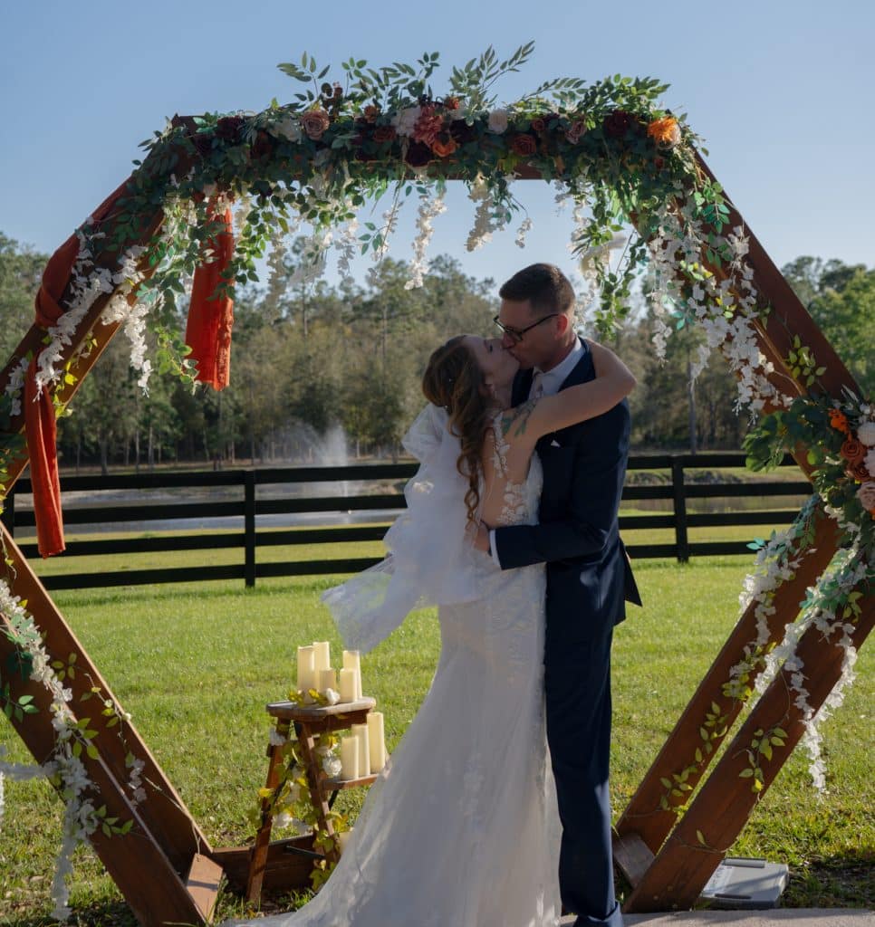 bride and groom kissing under the pergola adorned with greenery, Orlando, FL