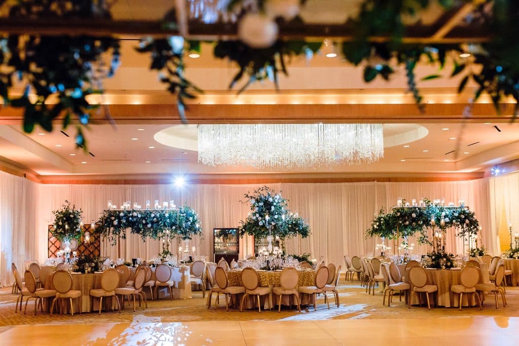 indoor reception set up, round tables with beautiful floral arrangements hanging above, as well as elevated centerpieces on each table, Orlando, FL