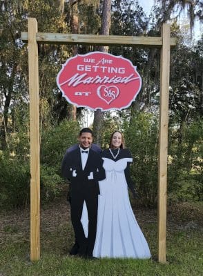 wedding couple standing under the We are getting married at S&S Ranch sign, Orlando, FL