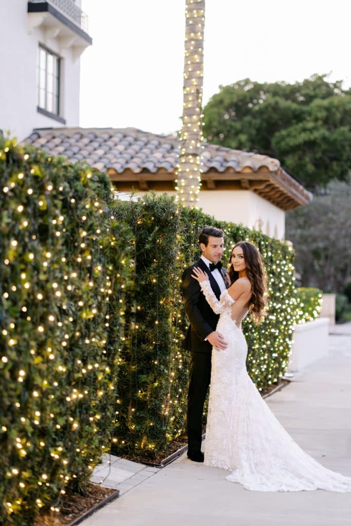 bride and groom standing outside their venue, grass walls covered with twinkle lights, Orlando, FL