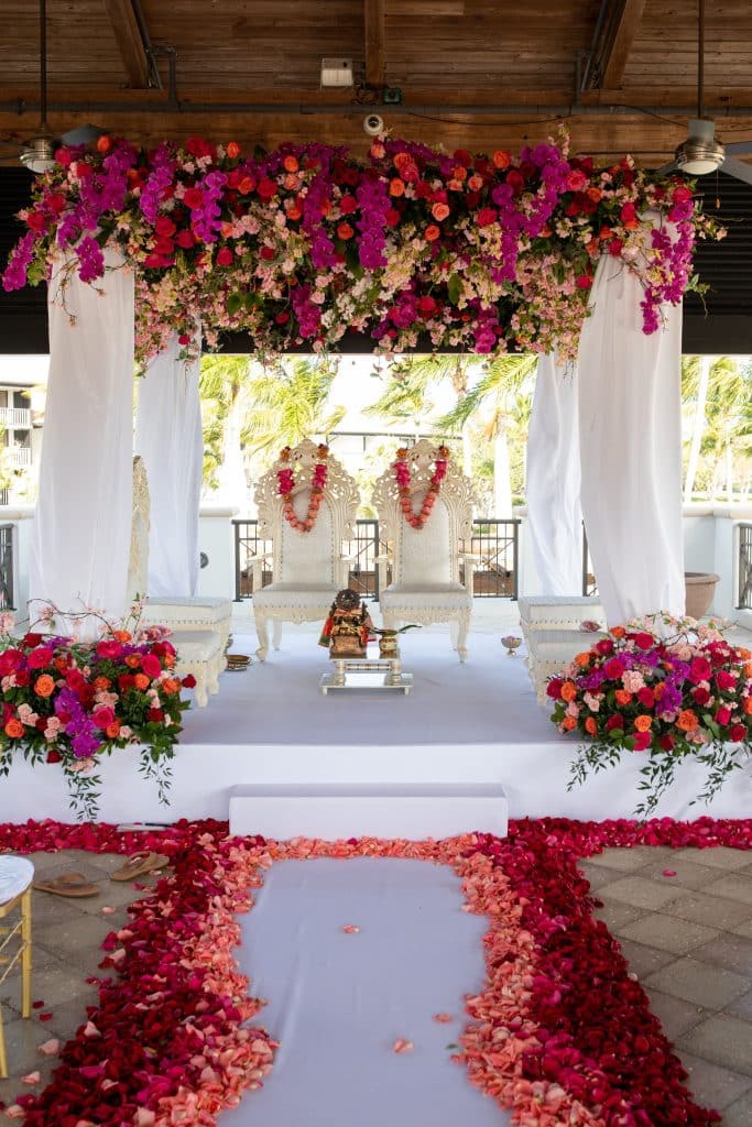 ceremony set up, pink and red flowers hanging above and on the ground, floral leis on mannequins at the altar area, Naomi Zora Events, Orlando, FL