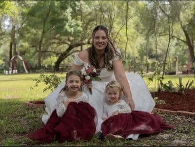 bride leaning down with her flower girl and ring bearer sitting in front of her, S&S Ranch, Orlando, FL