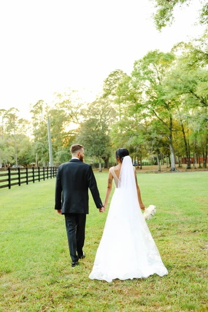bride and groom walking in their wedding attire on the ranch grounds, hand in hand, Orlando, FL