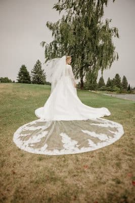 Bride in her wedding dress with her back towards the camera, white train spread out on the grass, Orlando, FL