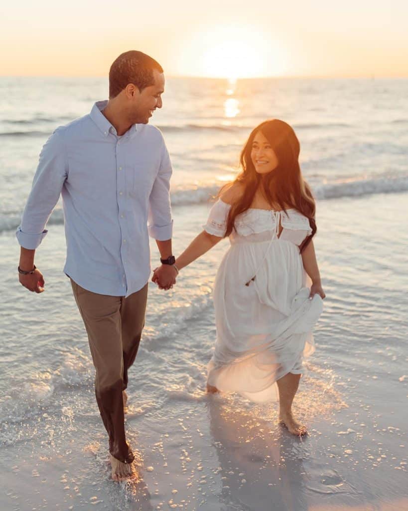 engagement photo shoot, happy couple holding hands on the beach, water beneath them, sunset, Lillie Shawn Imagery, Orlando, FL