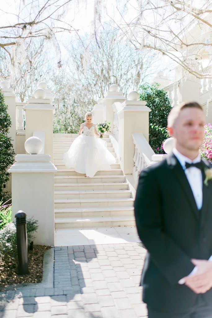 groom facing the camera with his bride on the staircase behind him, Orlando, FL