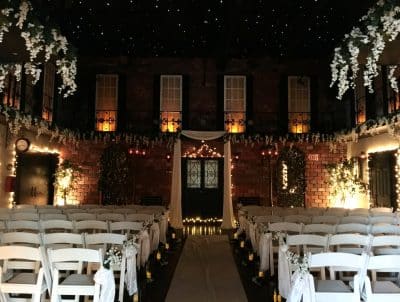 evening set up for a wedding ceremony, soft lighting, white chairs in rows, door decorated with white curtains and lights, at the end of the aisle, Gallery J, Orlando, FL