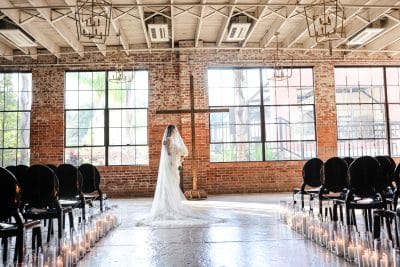 bride standing hear the altar at her wedding ceremony, room set up for the ceremony, large windows, black chairs, Hailey Beard Events, Orlando, FL