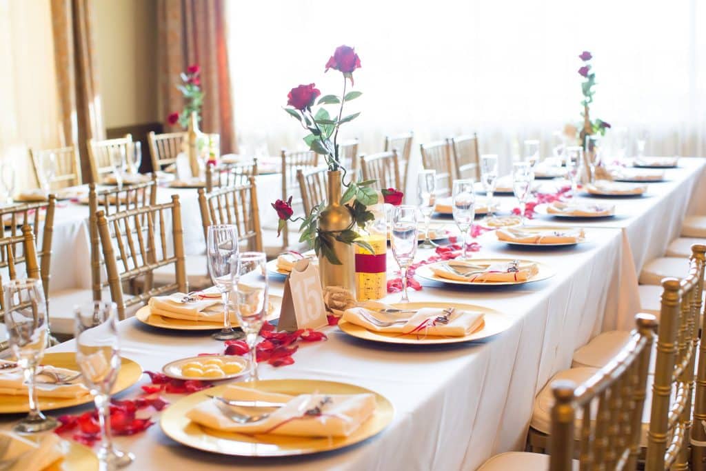 long dinner table set for 18, gold chairs, gold chargers, red petals on the table, white tablecloth, Falcon's Fire Golf Club, Orlando, FL