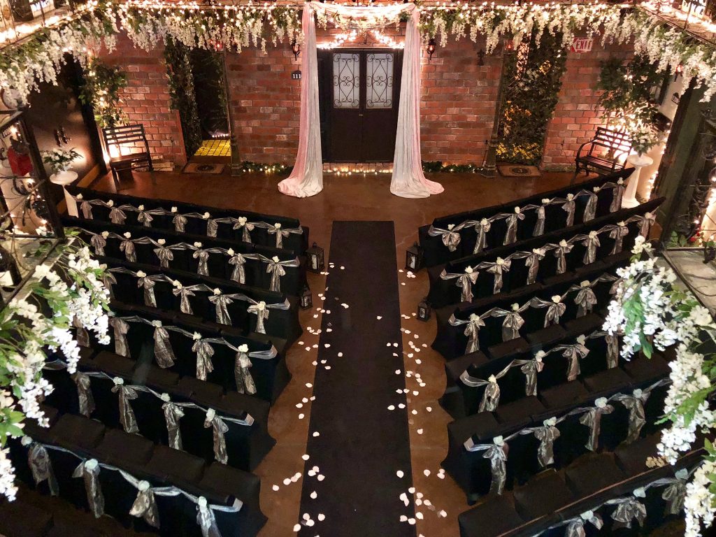 aerial view of the venue, chairs covered in black covers with white ribbons, door decorated with white curtains at the altar area, Gallery J, Orlando, FL