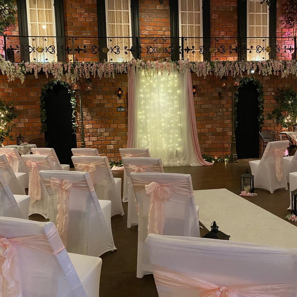 wedding ceremony set up, white chairs covered with white covers and adorned with pink bows, white carpet down the aisle, Orlando, FL