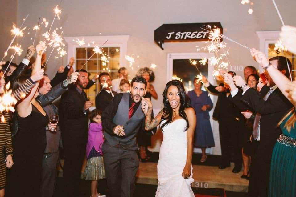 bride and groom walking through their receiving line where their guests are waving sparklers, Orlando, FL