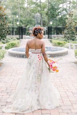 woman in her wedding dress, showing off the back of her dress, bride holding her bouquet, standing in front of the fountain, brick walkway, Orlando, FL