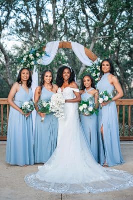 bride with her bridesmaids, dressed in light blue dressed, all holding their bouquets under the arch, Orlando, FL