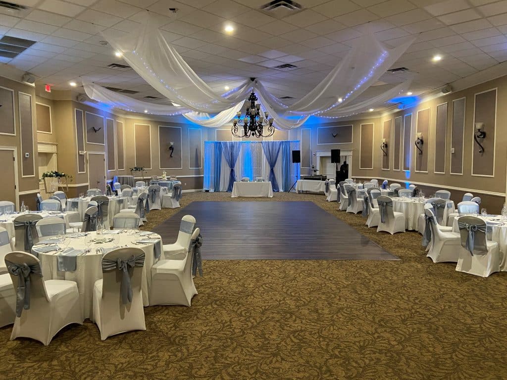 ballroom at Ventura Country Club, blue uplighting, dance floor, round tables with chair covers, light blue bows, Orlando, FL