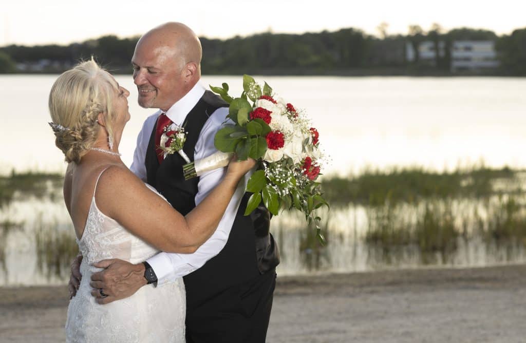 bride and groom embracing each other near the water, sunset, Ventural Country Club, Orlando, FL