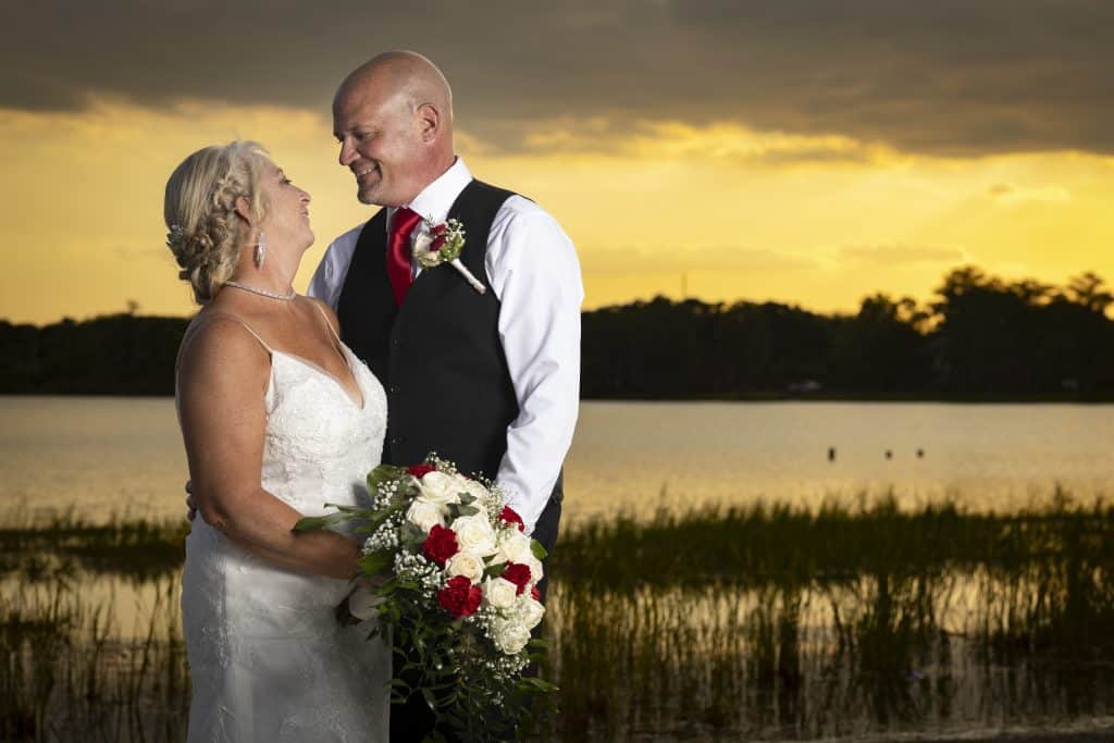 sunset, bride and groom gazing into each others eyes, water in the background, Orlando, FL