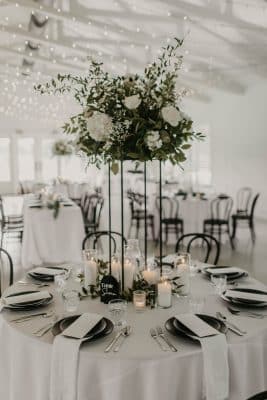 large, tall floral centerpiece with white flowers, white votive candles, round table, wine napkins, black plates, Orlando, FL