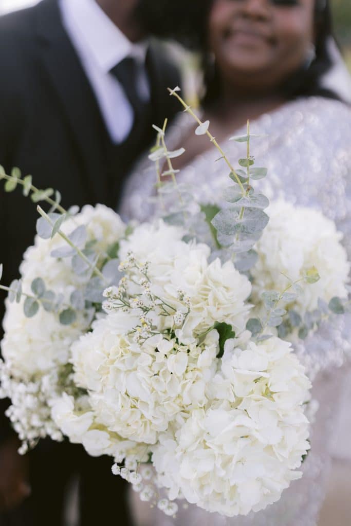 bride pushing her bouquet close to the camera lens, while her groom kisses her cheek, Orlando, FL